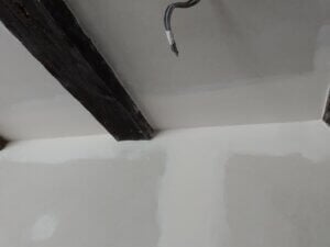 agencement intérieur : gros plan sur pose placo mur et plafond possédant des poutres en bois apparentes